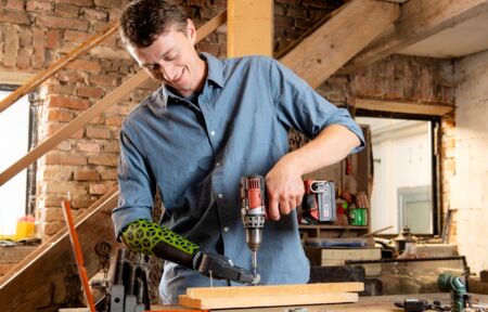 One-armed man uses Ottobock hand prosthesis while drilling.