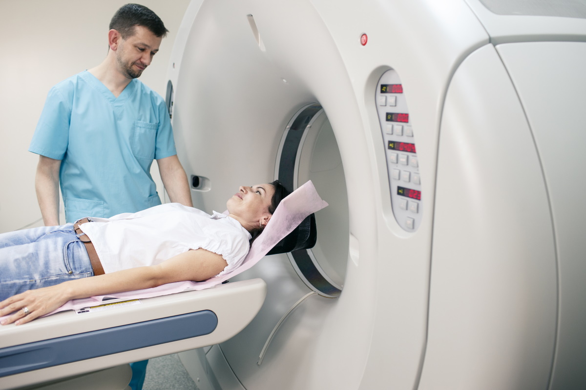 Eine Frau in einem hellen Hemd wird liegend in eine MRT-Röhre geschoben.