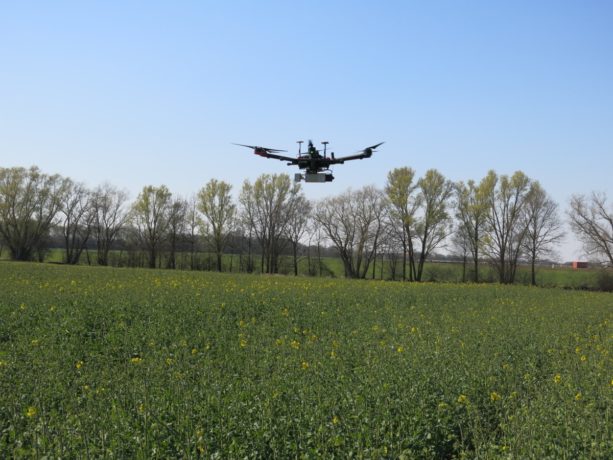 Eine Drohne fliegt über ein Feld.