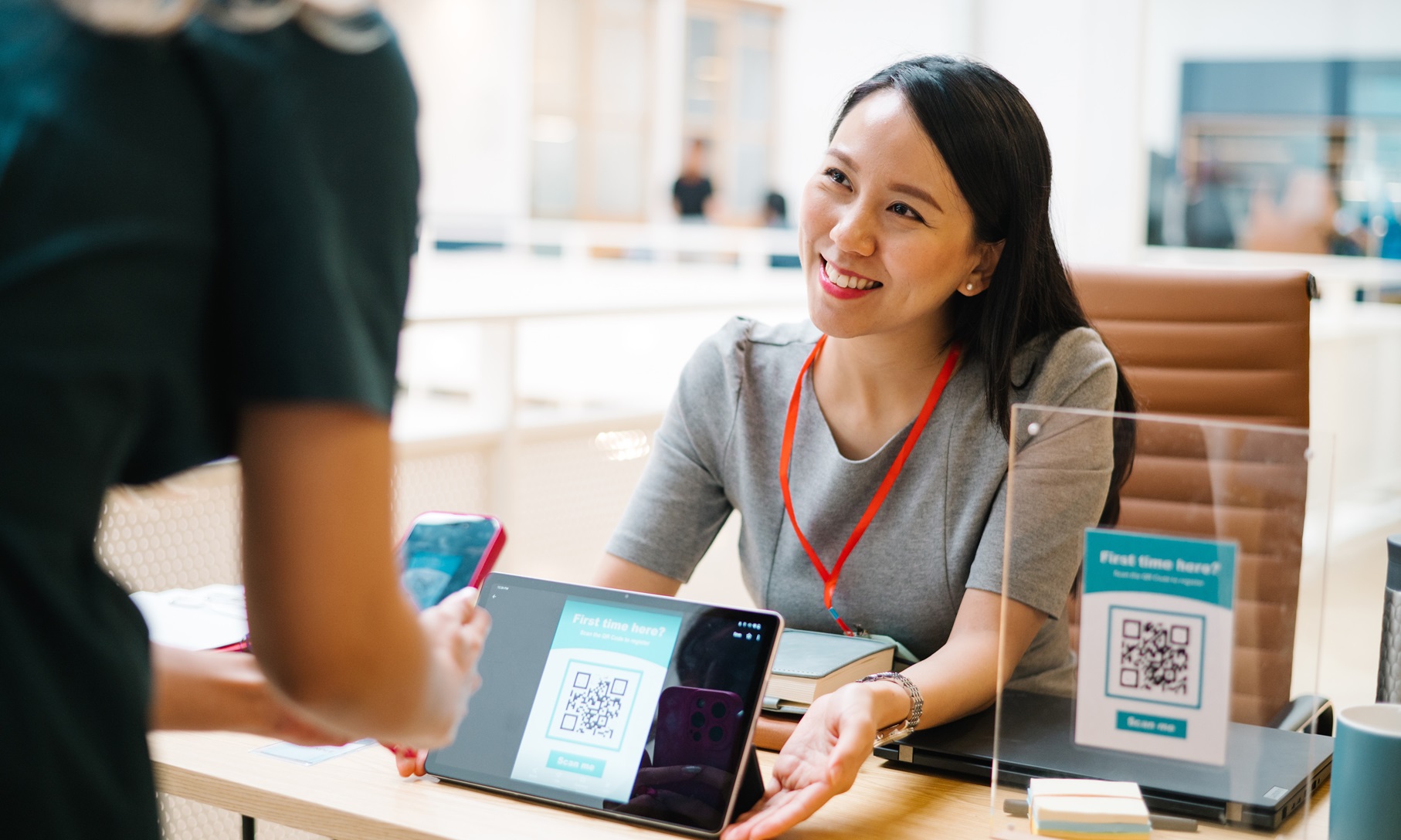 Frau scannt QR-Code, um sich vor Seminarbeginn anzumelden.