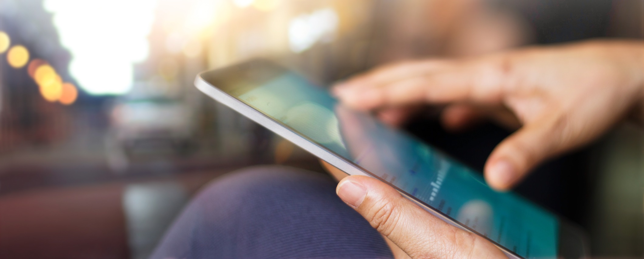 Eine Person hält ein Tablet in der Hand, der Hintergrund ist unscharf.